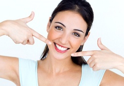 woman pointing to her smile with veneers in Downers Grove